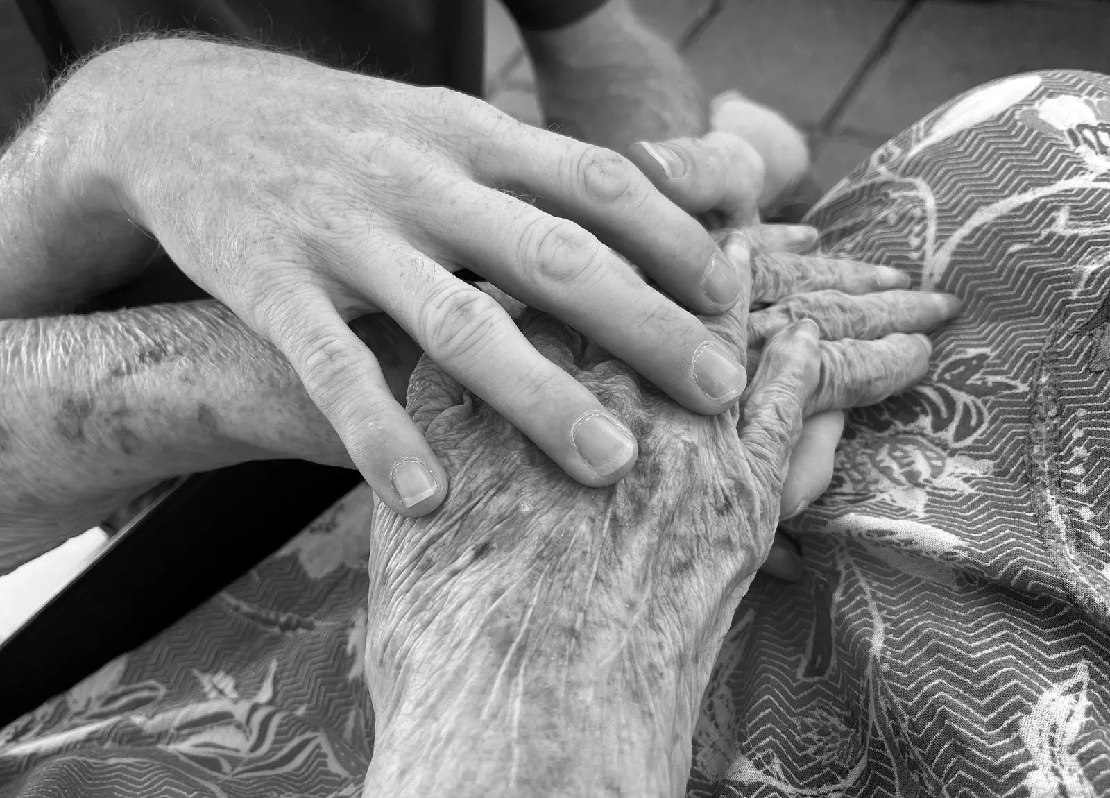 An older hand resting in a younger hand