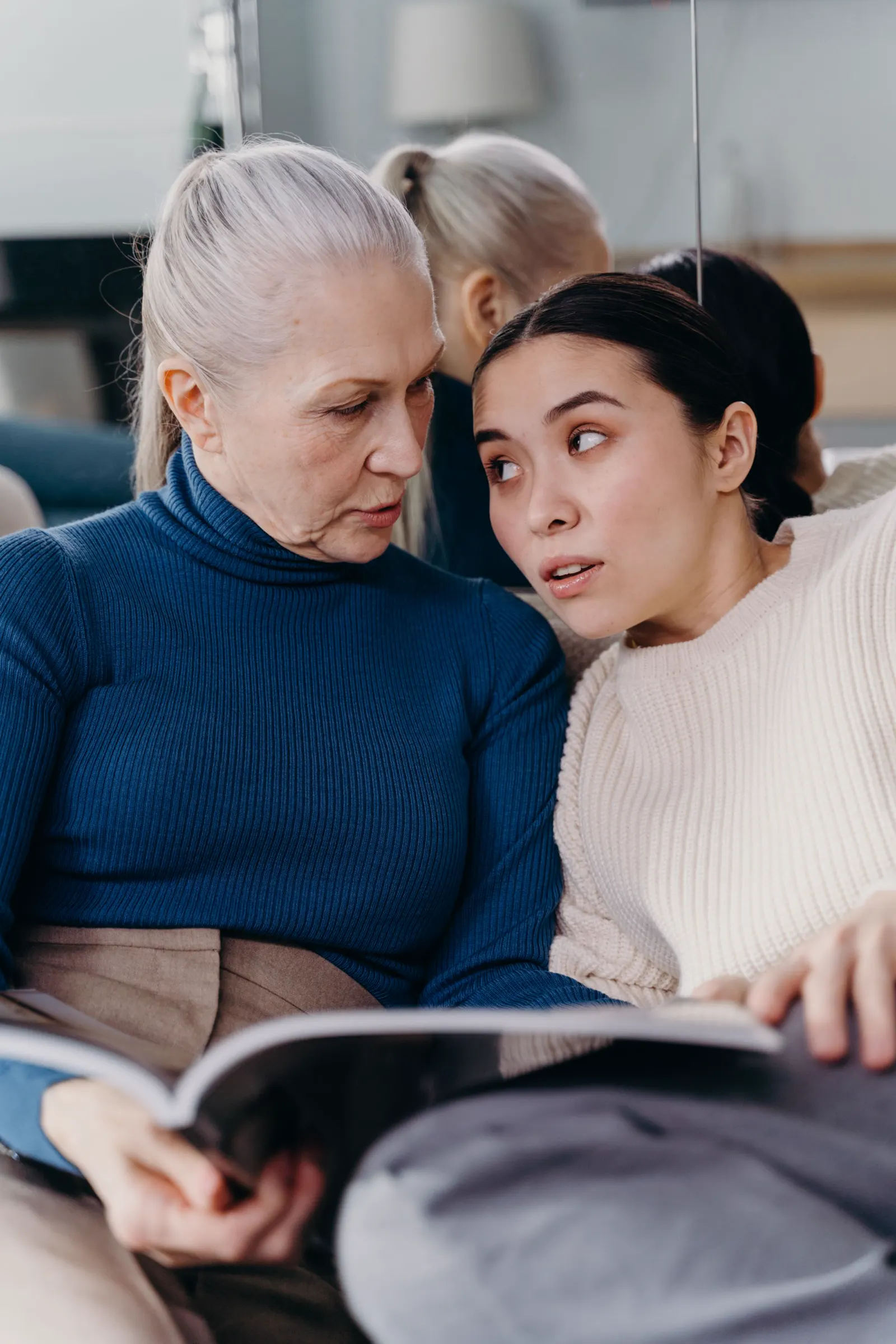 An older woman and a younger woman reading a magazine together