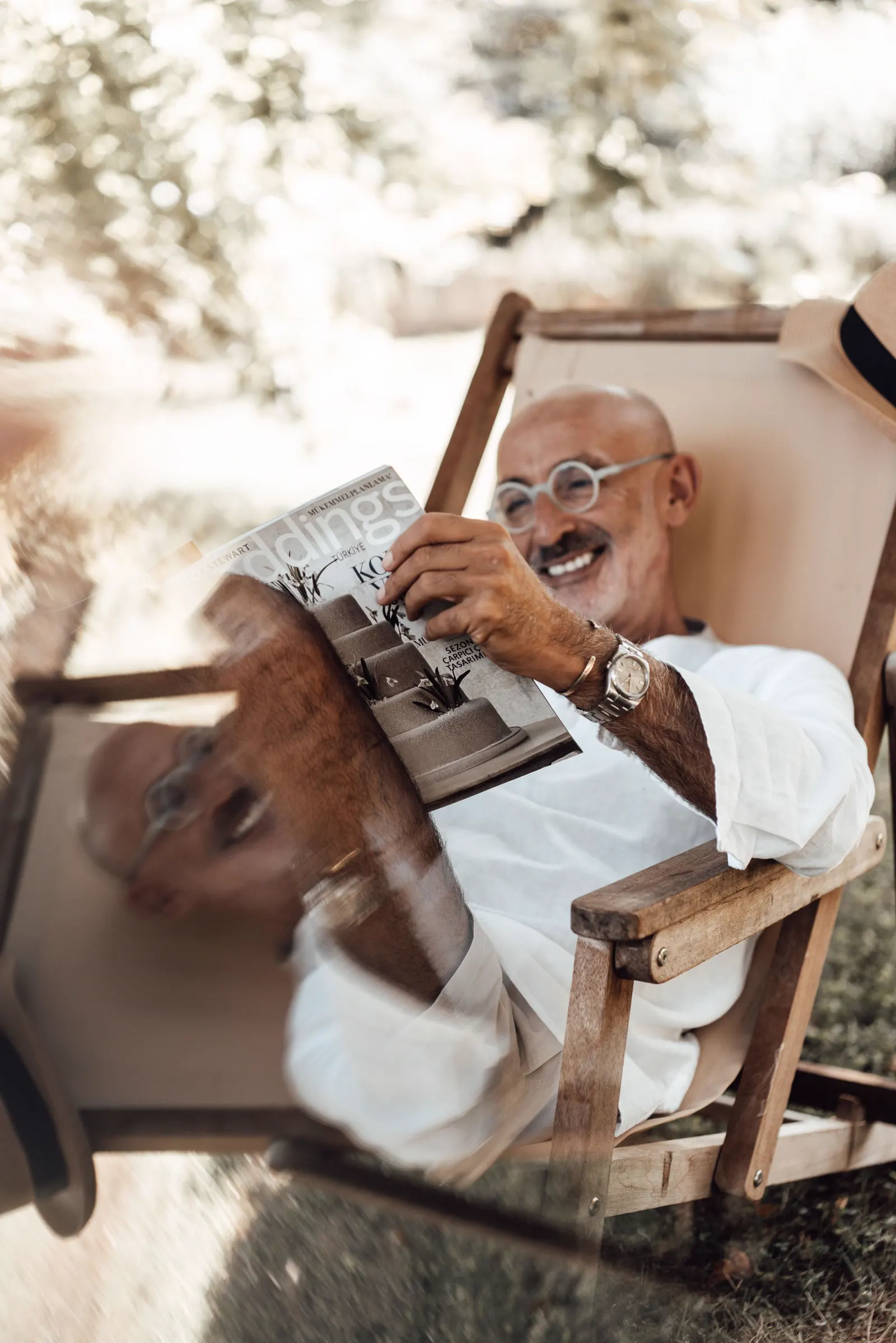 A smiling older man reading a magazine outdoors