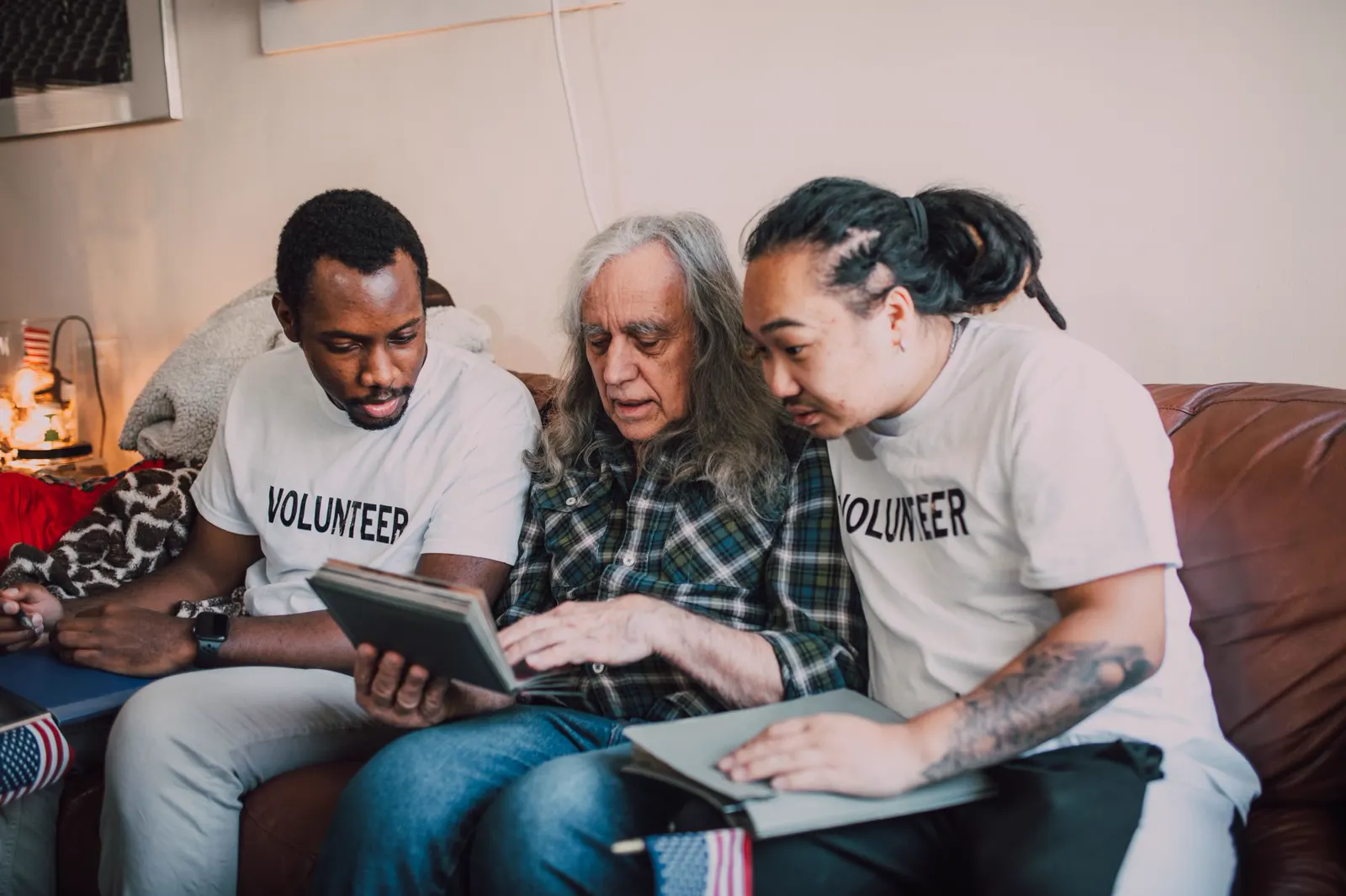 Two volunteers looking through a photo album with an older man