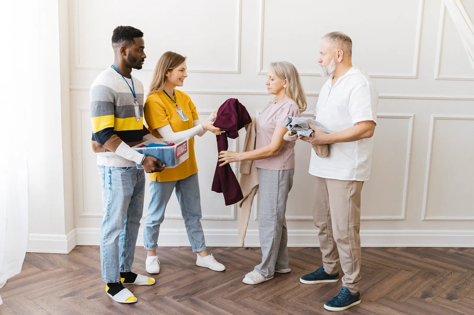 Volunteers greeting an older couple and handing them a gift
